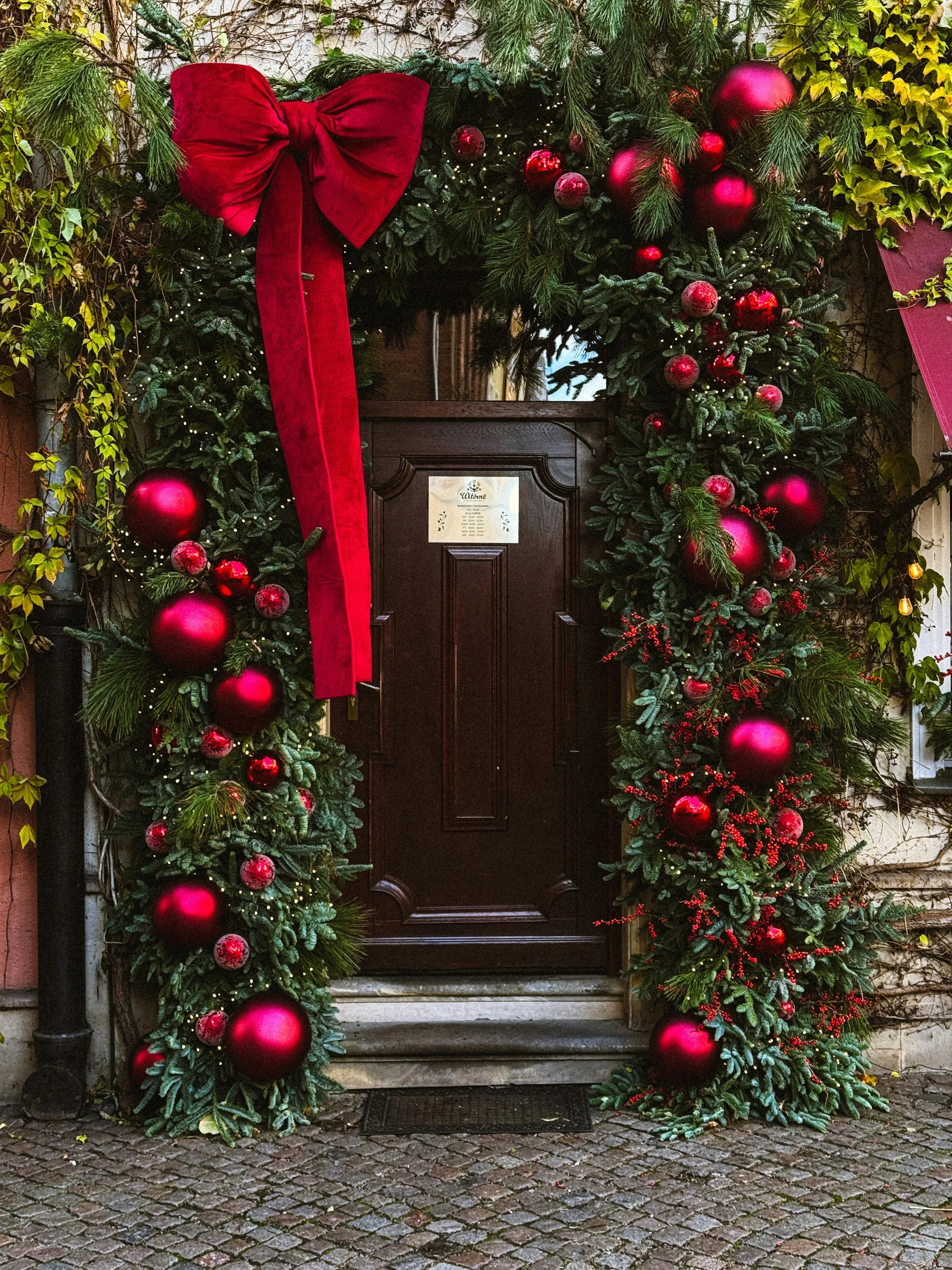 Grand holiday garland arch with red ornaments on classic door